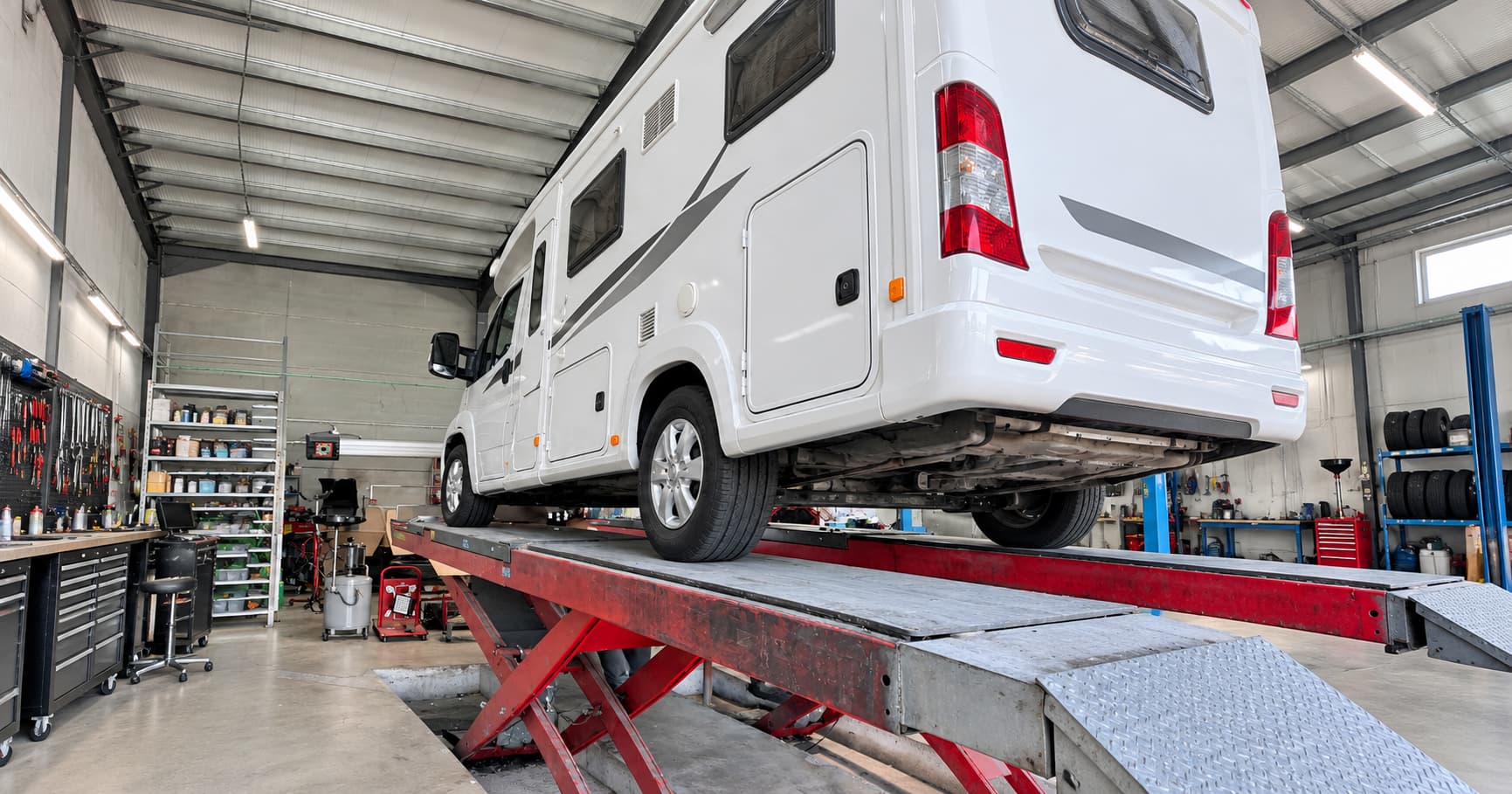 Autocaravana elevada en el taller para revisar bajos, neumáticos y frenos antes de un viaje largo